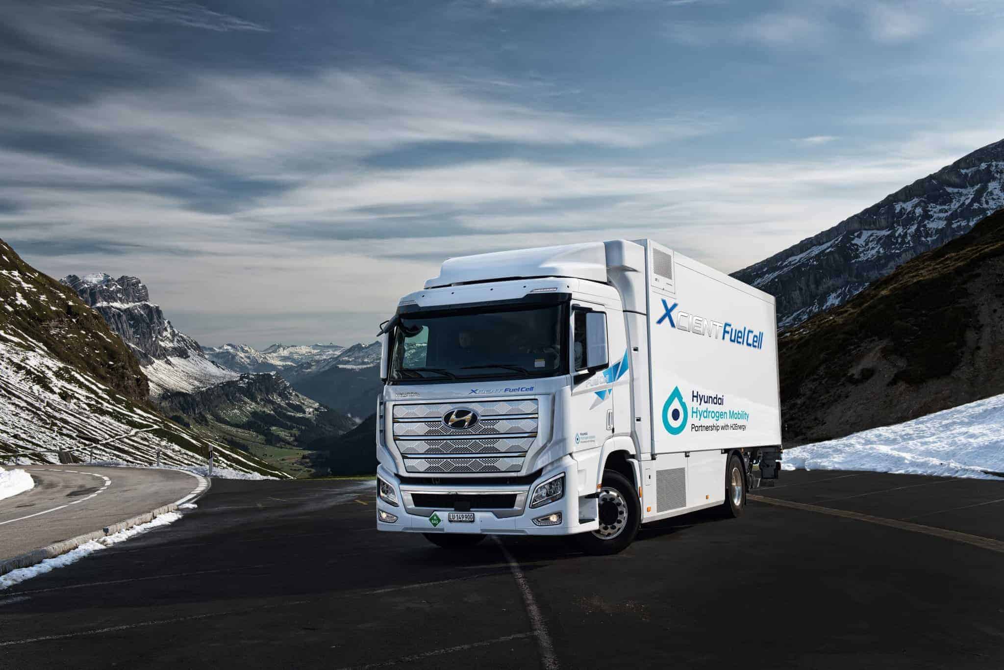 Un camion Hyundai à pile à hydrogène roule sur une route de montagne asphaltée, avec en arrière-plan des sommets et des vallées enneigés.